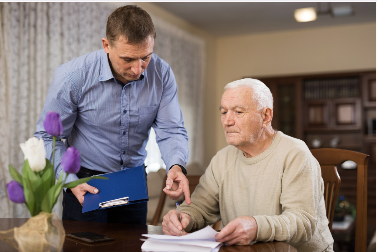 Adult man helping his senior father filling out financial documents at home